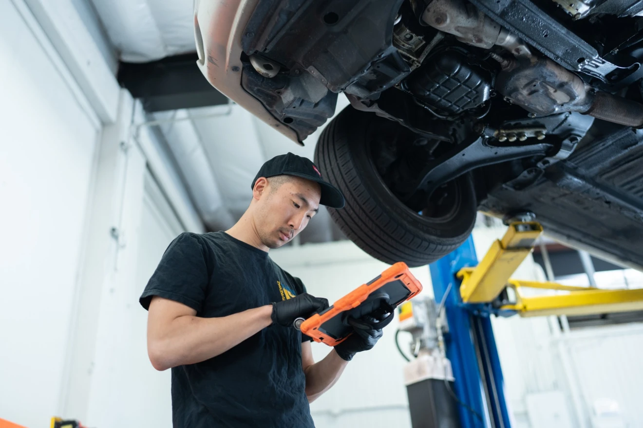 Technician with iPad inspecting vehicle